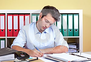 Laughing hispanic guy writing a message at office