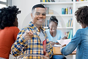 Laughing hispanic male student with braces learning with group of american students