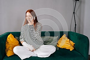 Laughing injured young woman with broken arm wrapped in gypsum bandage talking on smartphone with friends during