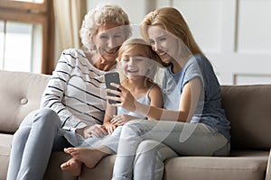 Laughing intergenerational family spending leisure time with smartphone at home