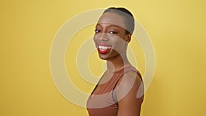 Laughing, joyous african american woman stands confident and smiling against a sunny, yellow isolated background, exuding