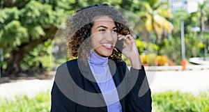 Laughing latin american businesswoman talking at phone