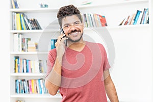 Laughing latin american hipster man talking at mobile phone