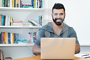 Laughing latin american man with hipster beard at computer