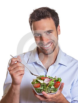 Laughing latin man eating salad