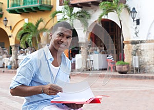 Laughing latin student in a colonial town with paperwork