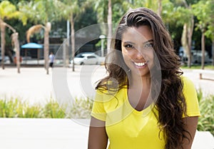 Laughing latin woman in yellow shirt looking at camera