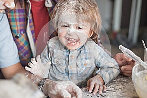 laughing little boy covered with flour while cooking