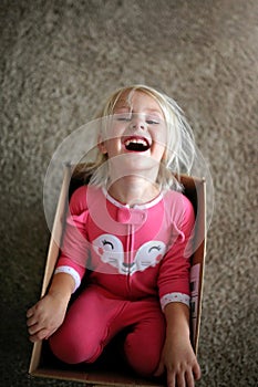 Laughing Little Child Playing in Large Cardboard Box at Home