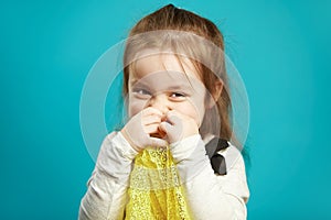 Laughing little girl covers her face with hands, smiles coquettishly and shyly, expresses embarrassment and shyness