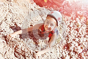 Laughing Little Girl in Protective Helmet climbing Rock