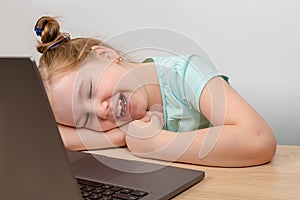 Laughing little girl using a laptop and speack via internet with her friends, relatives or teacher.