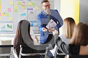 Laughing male speech giver stand in from of colleagues and explain something