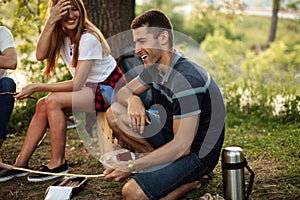 Laughing man is sitting with a stick on the grass