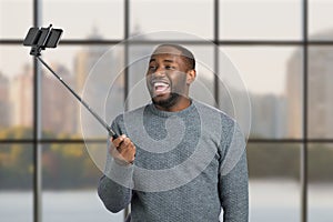 Laughing man taking selfie with monopod.
