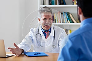 Laughing mature doctor with good news for patient