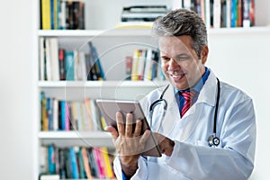 Laughing mature doctor with tablet computer