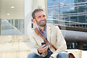 Laughing mature man sitting outdoors with cellphone