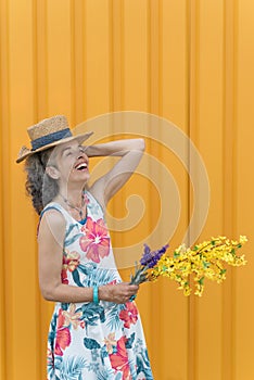 Laughing mature woman Flowers Straw hat Yellow background