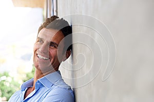 Laughing middle age man leaning against wall