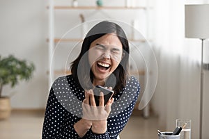 Laughing millennial asian woman watching cute comedy online by phone