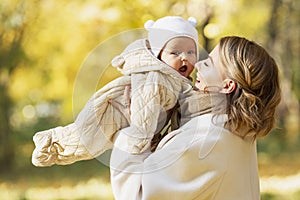 Laughing mom with her baby in an autumn park on a sunny day. Close-up. Love and tenderness