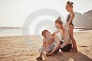 Laughing Mother and children sitting on a sandy beach