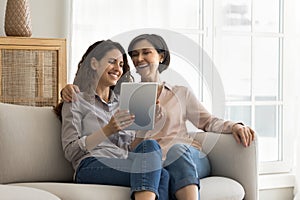 Multigenerational family sit on couch using modern digital tablet photo