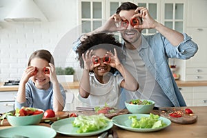 Laughing multiracial family making funny faces in kitchen.