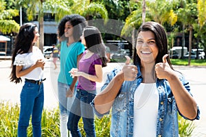 Laughing native latin american woman showing thumb with group of