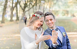 Laughing newlyweds show wedding rings on their hands