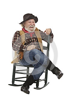 Laughing old cowboy sits in rocking chair