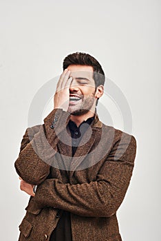 Laughing out loud. Young man covering his face with hand and laughing isolated on a white background