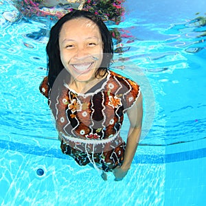 Laughing Papuan woman swimming in pool in brown dress