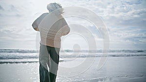 Laughing parent spinning kid on spring ocean beach. Joyful curly boy having fun