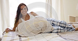 Laughing playful young woman relaxing in bed