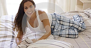 Laughing playful young woman relaxing in bed