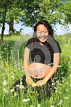 Laughing pregnant woman with drawing of baby on belly