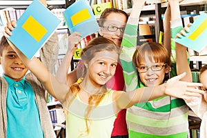 Laughing pupils with exercise books up in library