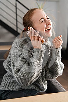 Laughing redhead sitting on the couch having a conversation on the phone at home