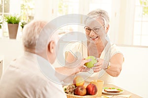 Laughing senior wife getting apple from husband