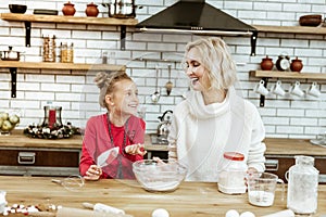 Laughing short-haired woman in oversize sweater listening to active child