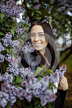 Laughing and smiling beautiful happy artistic young model girl with long hair in summer lilac garden with flowers posing