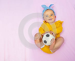 Little baby girl lay in bed with soccer ball toy