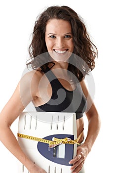 Laughing sporty woman with scale