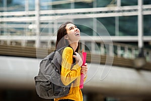 Laughing student walking with bag and books on campus