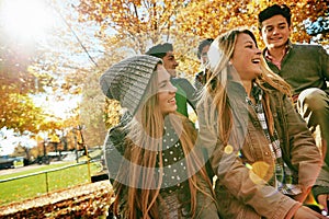 Laughing, talking and friends outdoor in park for relaxing day on summer vacation of semester break, together and photo