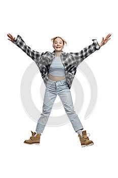 Laughing teenage girl jumping. Blonde girl in jeans, plaid shirt and yellow shoes. Movement and activity. Isolated on a white