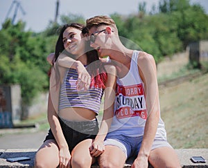 Laughing teenagers relaxing on a natural background. Romantic couple hugging in a city park. Young relationship concept.