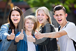 Laughing teenagers standing holding thumbs up